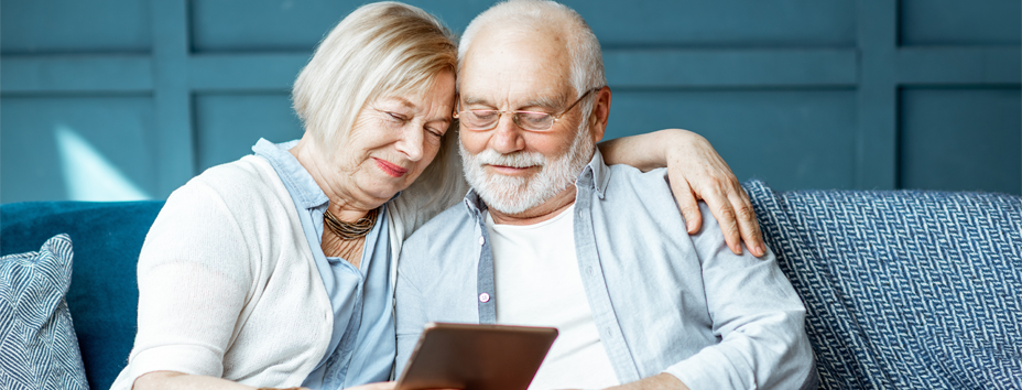 Older couple sitting on couch reading IPad